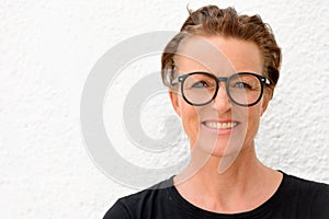 Face of beautiful mature woman wearing big eyeglasses and smiling while standing against white background outdoors