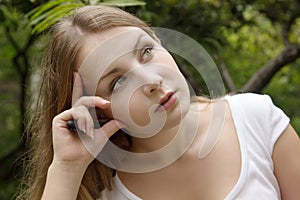 Face of beautiful serious girl in green summer park