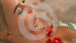 Face beautiful woman bathing in jacuzzi water with rose petals in spa. Portrait woman lying in jacuzzi tub in luxury spa