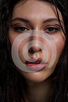 The face of a beautiful young girl with wet black hair close-up. Eastern appearance. Nude makeup, natural skin.