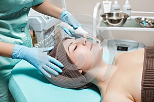 Face Beauty Treatment. Beautician makes Facial Darsonval Therapy for woman photo