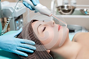 Face Beauty Treatment. Beautician makes Facial Darsonval Therapy for woman photo