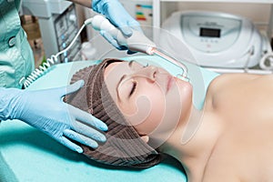 Face Beauty Treatment. Beautician makes Facial Darsonval Therapy for woman photo