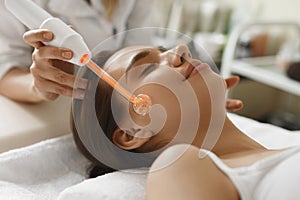 Face Beauty Treatment. Woman Using Darsonval Skin Care Device