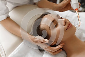 Face Beauty Treatment. Woman Using Darsonval Skin Care Device