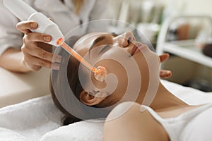 Face Beauty Treatment. Woman Using Darsonval Skin Care Device photo