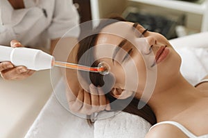 Face Beauty Treatment. Woman Using Darsonval Skin Care Device photo