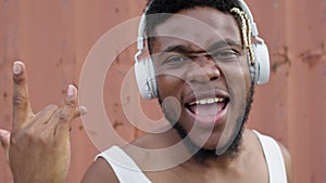 Face of black young guy in headphones. He listens to music and dances. Plastically moves his shoulders and arms.