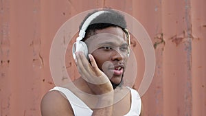 Face of black young guy in headphones. He listens to music and dances. Plastically moves his shoulders and arms.