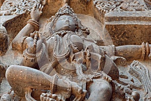 Face, breast of female Hindu god on old sculpture wall. Relief of 12th century Hoysaleshwara temple in Halebidu, India