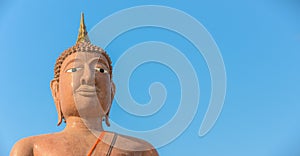 Face of Buddha statue isolated on blue background with copy space for text