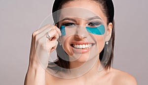 Face care. Beautiful woman with professional make-up and eye patches