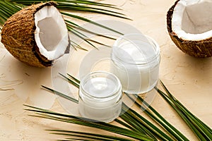 Face care. Coconut cream in glass jar on beige background