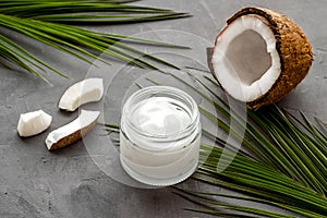 Face care. Coconut cream in glass jar on grey background