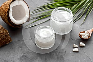 Face care. Coconut cream in glass jar on grey background