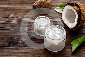 Face care. Coconut cream in glass jar on wooden background copy space