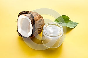 Face care. Coconut cream in glass jar on yellow background