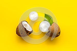 Face care. Coconut cream in glass jar on yellow background top-down