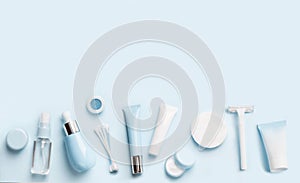 Face care products tonic or lotion, serum, cream, micellar water, cotton pads and sticks, shaver on blue background. photo