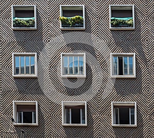 Face of cement apartment building with 9 symmetrical windows in Bologna Italy