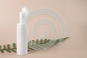 Face cleanser, facewash dispenser, beauty skincare cosmetic in pump container with green leaf on a natural background