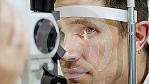 Face close-up , man doing eye test with non contact tonometer, cheking vision, intraocular pressure at optical clinic