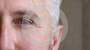 Face closeup of an older man with grey hair looking calm, staring and blinking. Head portrait of a senior psychologist