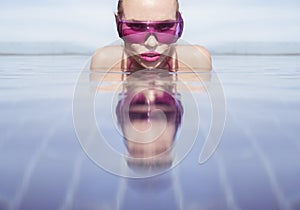 Face closeup of woman in purple sunglasses in infinity rooftop swimming pool