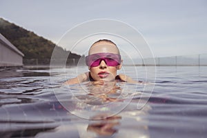 Face closeup of woman in purple sunglasses in infinity rooftop swimming pool