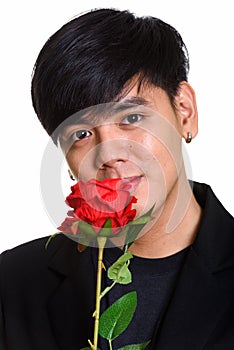 Face of cool handsome Asian man smelling red roses