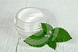 Face cream in glass jar with green leaf of urtica photo