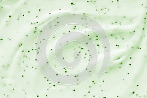 Face cream scrub texture background. Green color exfoliating skincare product smear photo