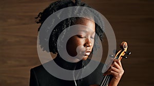 Face, creative and violin with black woman musician in studio on wooden wall background for orchestra performance