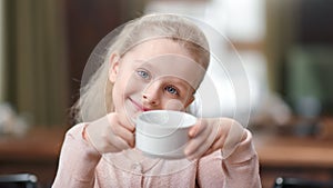 Face of cute baby girl holding cup of tea posing at cafe have fun. close up shot on 4k red camera