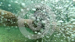 The face of a diver diving in a mask with a snorkel under the water. Slow-motion underwater selfie among air bubbles.