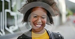 Face of an edgy young woman with afro smiling. Portrait of beautiful trendy black girl laughing, showing her teeth
