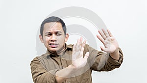 Face expression of young Asian Malay man in casual shirt closing and covering his eyes from something in front
