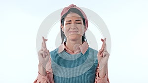 Face, fingers crossed and woman with hope, wish and promotion on a blue studio background. Portrait, person and model