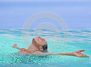 Face, freedom and rain with woman in swimming pool for travel, holiday or vacation as tourist. Relax, smile and wet in
