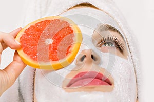 Face fruit peeling mask, spa beauty treatment, skincare. Young woman getting facial care at spa salon, mud clay mask on