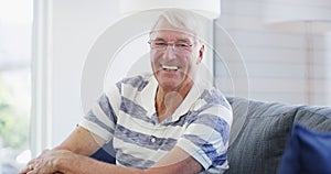 Face, funny and senior man on sofa at home, happy and excited for retirement in living room. Portrait, elderly person