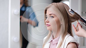 Face of girl at beauty salon hair styling on curling iron close up. Shot with RED camera in 4K