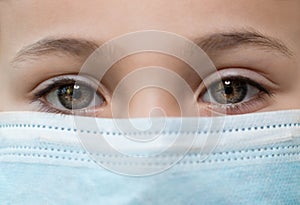 Face girl with red eyes and a medical mask on a black background, copy space. Concept of people who are isolated in a coronavirus