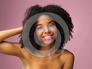 Face, hair care and happy black woman with makeup in studio isolated on a pink background with eyeshadow. Hairstyle