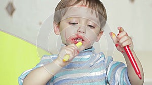 The face of a happy child, drawn by a felt-tip pen. A dirty child laughs and plays. The child is painted in colors.