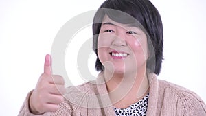 Face of happy overweight Asian woman giving thumbs up ready for winter