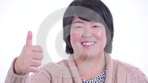 Face of happy overweight Asian woman giving thumbs up ready for winter