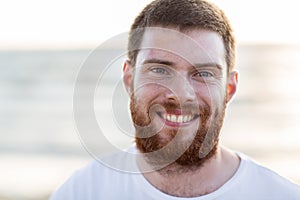 Face of happy smiling young man on beach