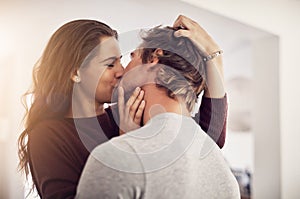 Face of happy woman, man and kiss with love in apartment for romance, intimacy and special moment together. Young couple