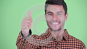 Face of happy young Hispanic hipster man giving thumbs up